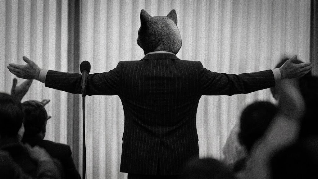 The dog in a pinstripe suit, arms wide, back to the crowd.